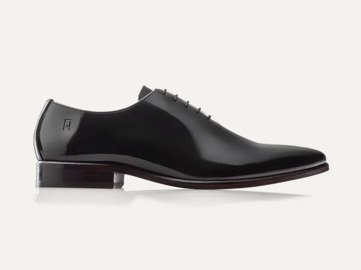 Sapato Oxford Classic Wholecut em couro preto, sobre fundo claro.