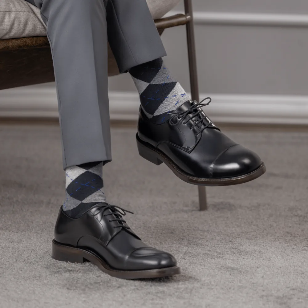 Pernas cruzadas de um homem com calça social e sapatos combinando.