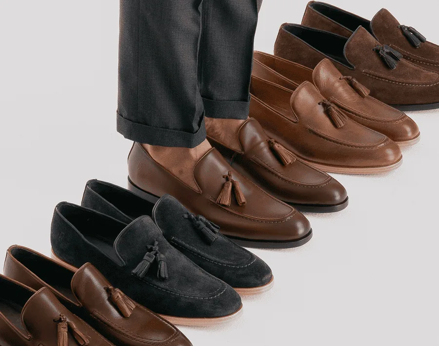 Fileira de loafers em couro e camurça, vistos de cima.